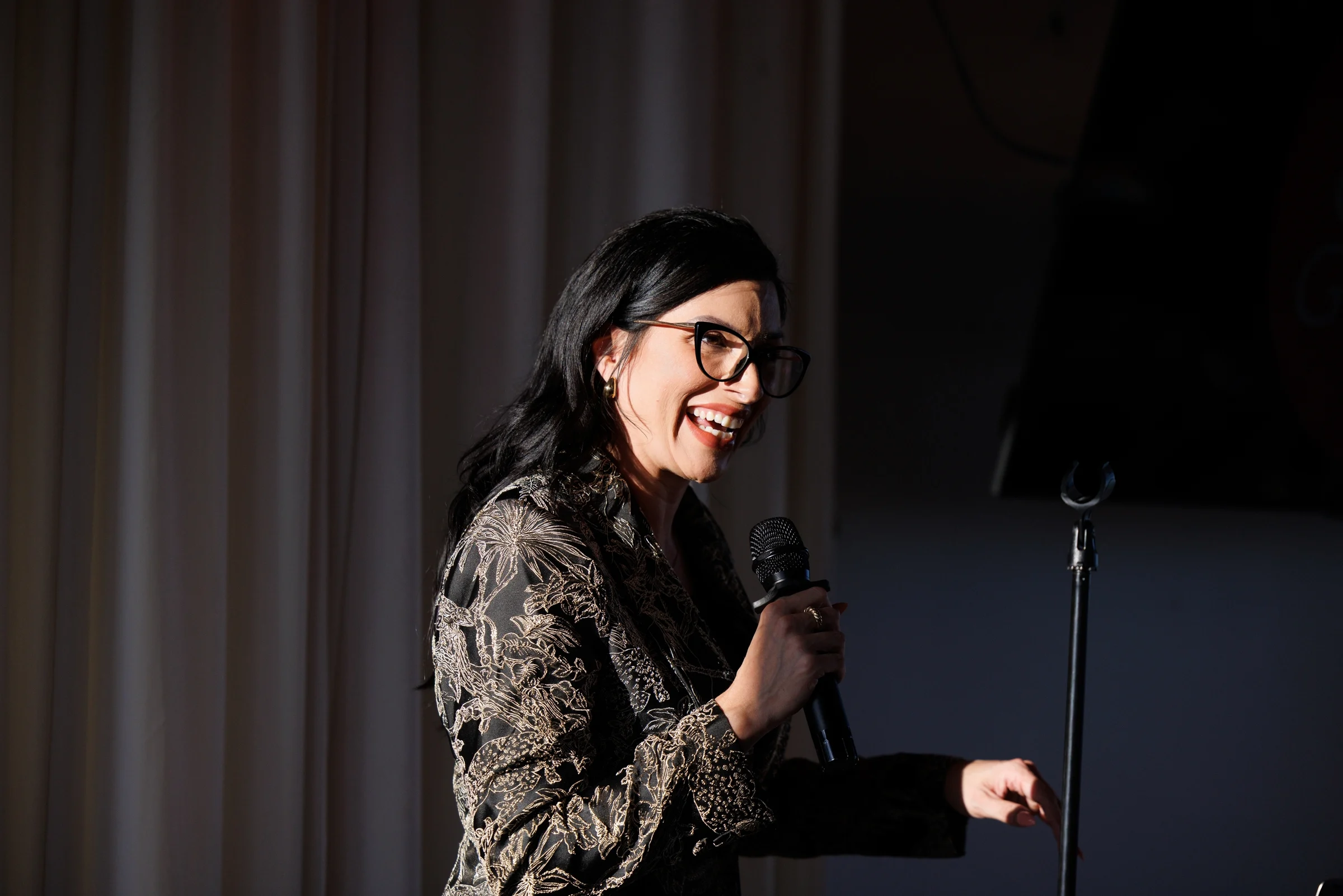 Speaker smiling with a microphone on stage