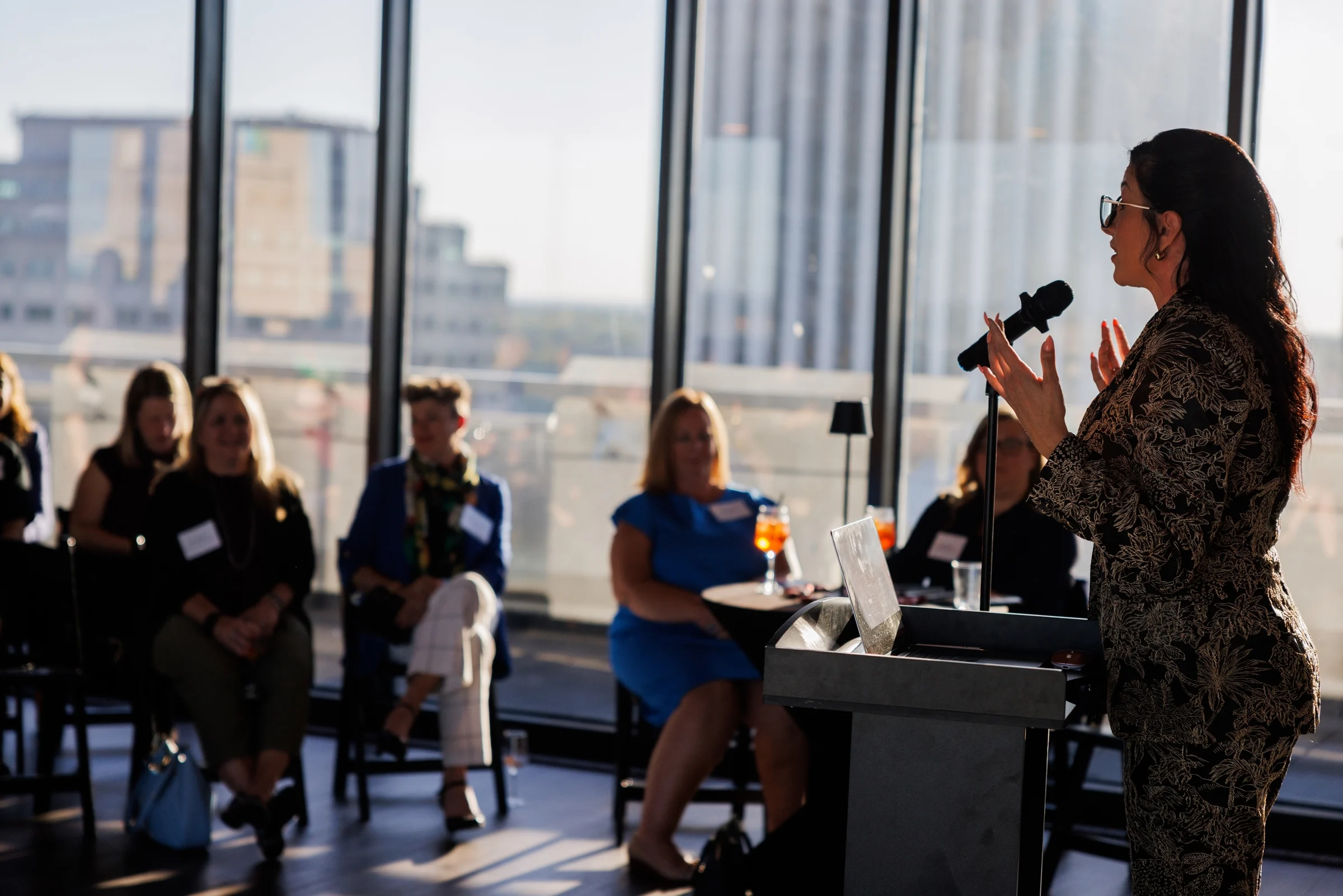 Speaker addressing guests beneath the event presentation
