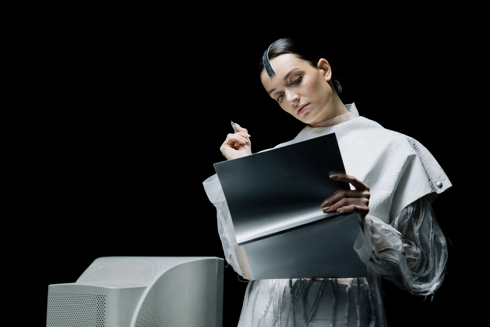 Woman reviewing a portfolio beside a computer against a dark background